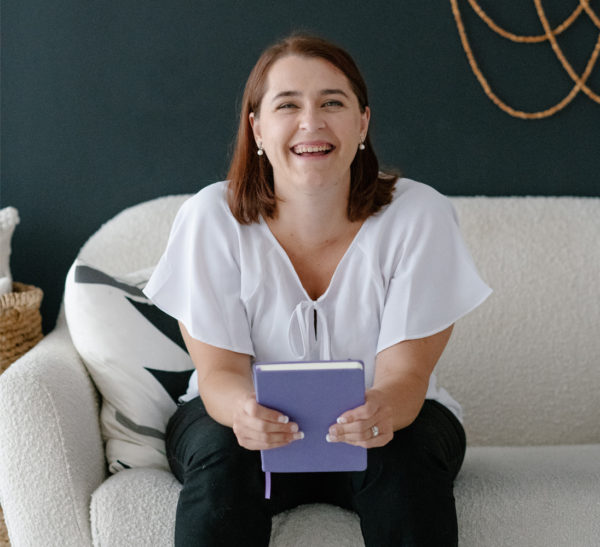 Melanie Ziltener sitting on a sofa being a content strategistwith her notebook